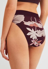 Bordeaux bloemen bikini slip gemaakt van zacht materiaal. Heeft een hoog uitgesneden ontwerp met grote bloemenpatronen in lichte kleuren op de achterkant.