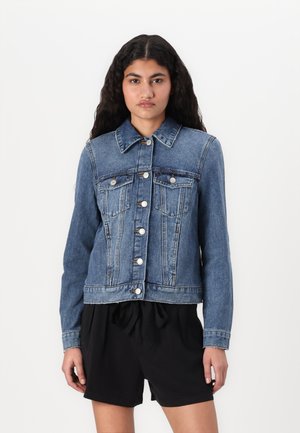 Džíská z denimu ve středně modré barvě s knoflíkovým zapínáním, dvěma hrudními kapsami a dlouhými rukávy. Má klasický límec a strukturovaný střih.
