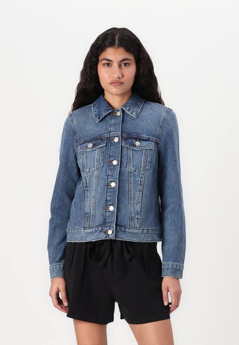 Chaqueta de mezclilla en azul medio con cierre de botones en la parte delantera, dos bolsillos en el pecho y mangas largas. Presenta un cuello clásico y un ajuste estructurado.