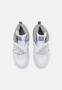 Bijele atletske cipele s kožnom gornjom, sivoj akcentima, perforiranim prednjim dijelom i podesivim remenom s "SKYJORDAN" grafikom i logom.