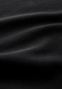 Black fabric with a smooth, slightly glossy texture, featuring subtle folds and creases highlighting its soft, flexible quality.