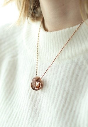 Roze gouden pendant ketting met verstrengelde lussen, waarvan er een versierd is met kleine heldere kristallen, hangend aan een delicate bolletjesketting.