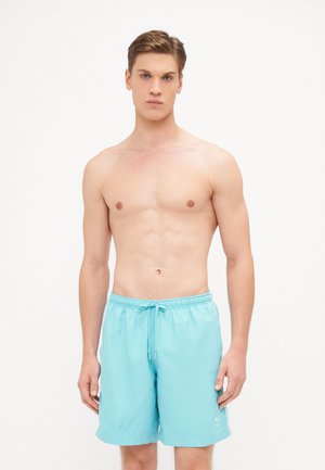 Pantaloni da bagno azzurri chiari realizzati in tessuto a rapida asciugatura, dotati di una vita elastica con coulisse e un piccolo logo sul lato.