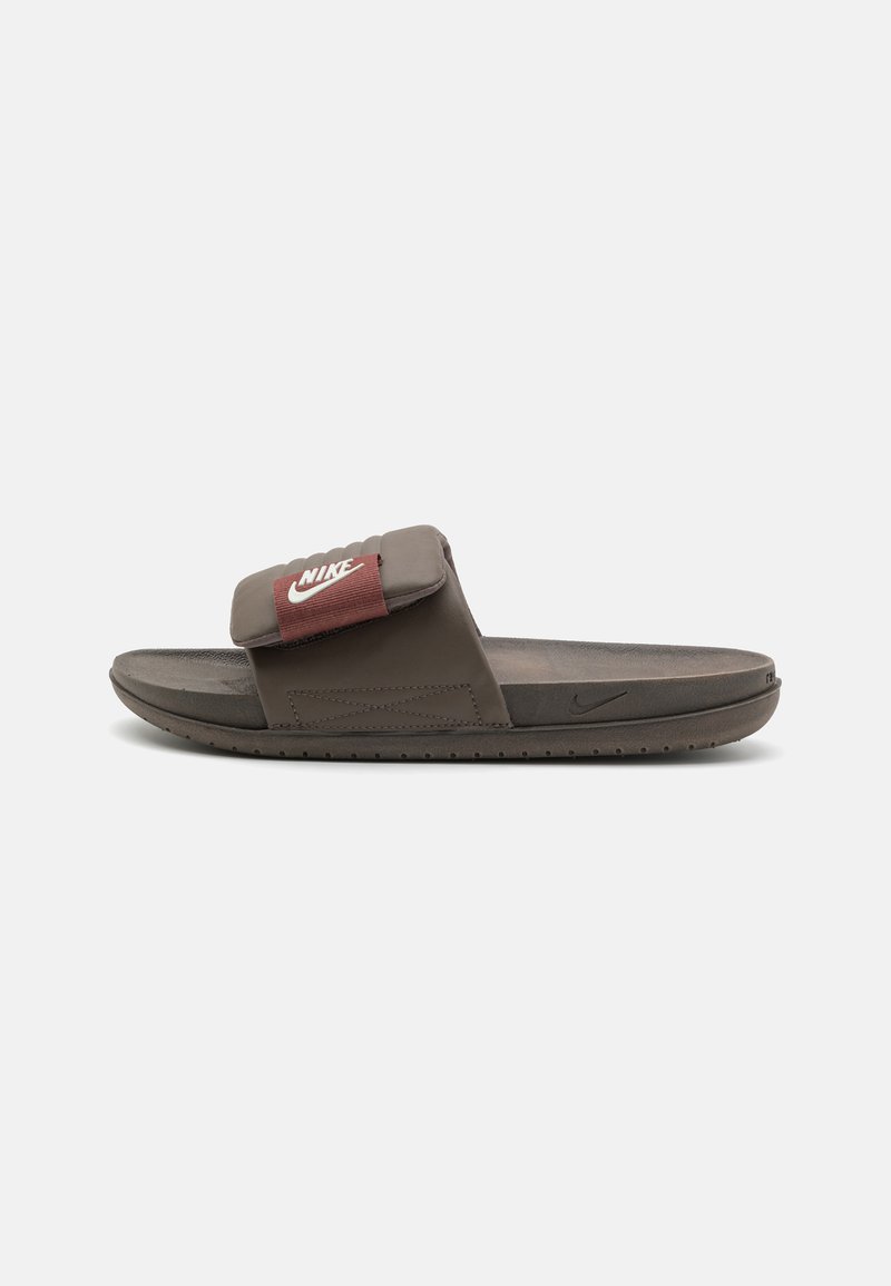 Barna Nike diák szandál párnázott pánttal, piros kiegészítővel és logóval, texturált talppal és rugalmas gumitalppal.