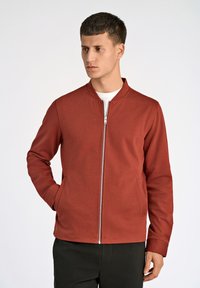 Röd zip-up jacka med krage, tillverkad av ett slätt, strukturerat tyg. Har sidofickor och en figurnära silhuett.