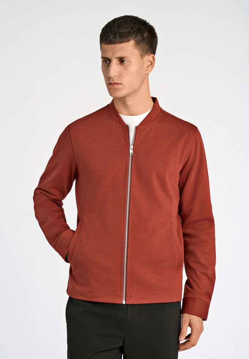 Röd zip-up jacka med krage, tillverkad av ett slätt, strukturerat tyg. Har sidofickor och en figurnära silhuett.