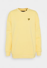 Sudadera amarilla de manga larga, con cuello redondo y puños acanalados. Presenta un pequeño logo de pájaro negro en el pecho. Textura de tela suave.