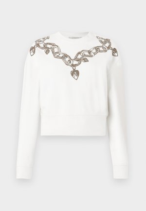 Valkoinen lyhyt hiha sweatshirt, jossa on pitkät hihat, ja kaula-aukossa sekä olkapäillä metallilangasta tehty ketju- ja sydäntyyppinen kuvio.