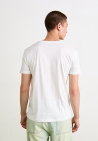 Hvid bomuld t-shirt med korte ærmer og rund hals, der har en blød tekstur og et enkelt design, set fra ryggen.