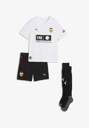 Hvid kortærmet fodboldtrøje med Valencia CF-logo og TM Real Estate som sponsor, sorte shorts og sorte knæstrømper med Puma-logoer.