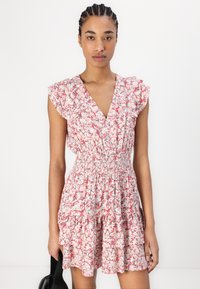 Φλοράλ φόρεμα σε ροζ και λευκό με βολάν μανίκια, ελαστική μέση και στρωμνή φούστα. Το ύφασμα έχει μια ελαφριά, υφασμάτινη εμφάνιση.