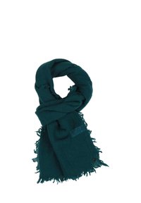 Écharpe turquoise en tissu doux et texturé, avec des bords effilochés et une petite étiquette d'accent avec un bouton. Enroulée en une boucle lâche.