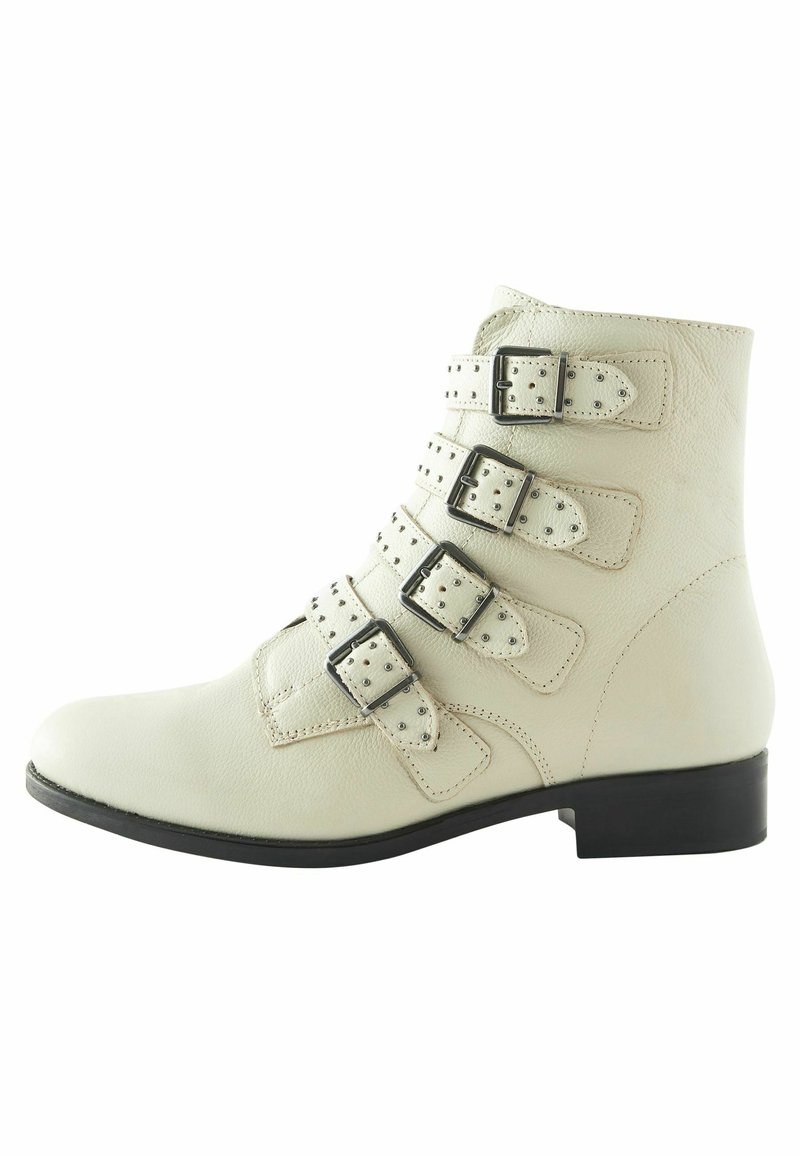 White leather ankle boot with four adjustable straps and silver buckles. Features a low black heel and a smooth textured finish.