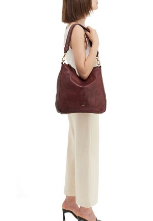 Borsa a spalla in pelle marrone con una forma curva, trama liscia e accenti in metallo dorato. La borsa ha un'apertura ampia e una tracolla sottile.