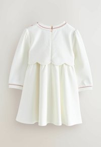 Weißes Kleid mit langen Ärmeln, gewelltem Saum und einem pinken Akzent an den Bündchen. Mit einem Reißverschluss auf der Rückseite. Glattes, strukturiertes Material.