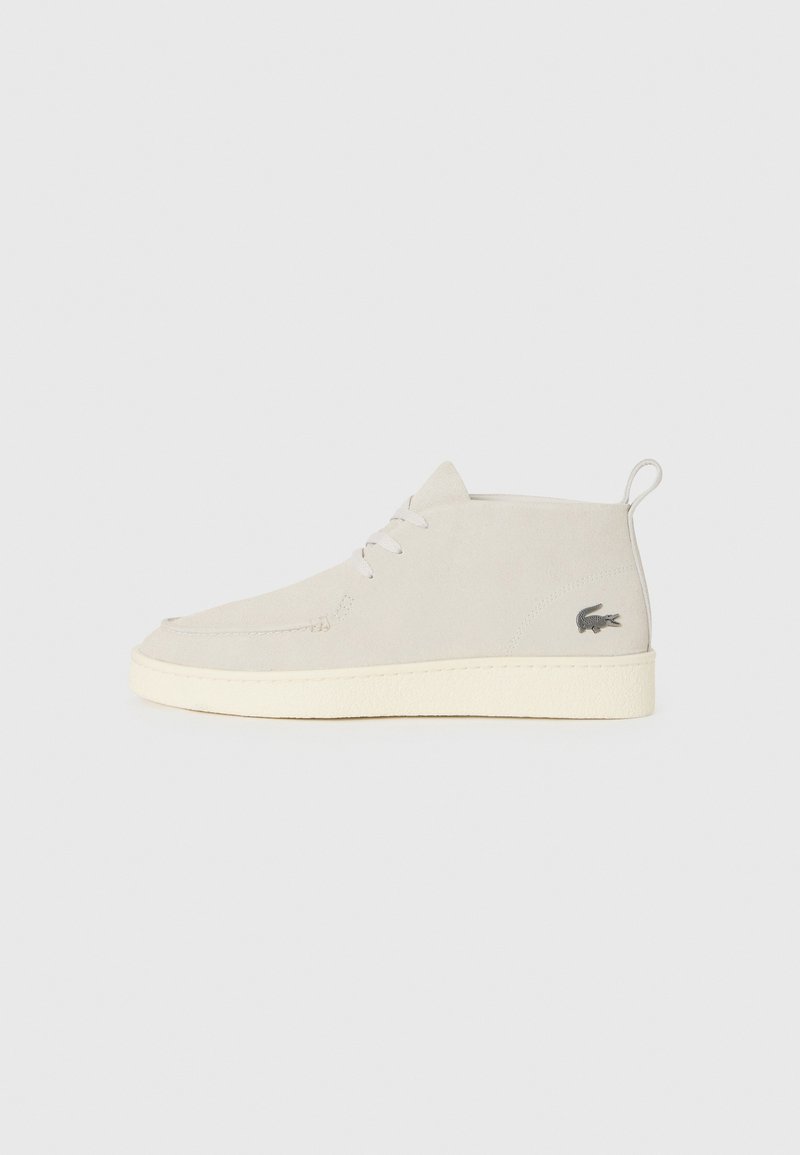 Bottines en suède gris clair avec un bout rond, semelle en caoutchouc blanc et détail de logo subtil sur le côté. Elles présentent un système de laçage.