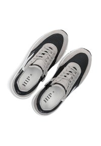 Schwarze und graue Sneakers mit Netzpanels, Wildlederakzenten, flachen Schnürsenkeln und einer weißen Sohle. Der Markenname "HIP" ist auf der Innensohle sichtbar.