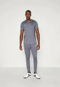 Grijze sportieve t-shirt en bijpassende smalle broek gemaakt van lichtgewicht stof. Kenmerkend zijn de subtiele logo-accenten en het slanke ontwerp.