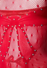 Κόκκινο ύφασμα ψαθωτού πλέγματος με διαμάντι σχήματος διακοσμητικά σχέδια, περιγράμματα από μικρές στρογγυλές στρας, δημιουργώντας ένα διακοσμητικό και υφασμάτινο σχέδιο.