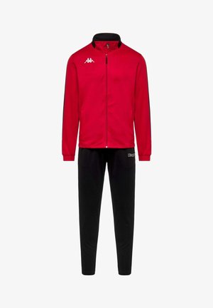 Veste rouge zippée avec logo blanc sur la poitrine, associée à un pantalon noir avec logo sur la cuisse, présentée sur fond blanc.