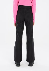 Pantalons larges noirs en tissu texturé avec un motif pied-de-poule, dotés d'une taille haute et de bords à revers.