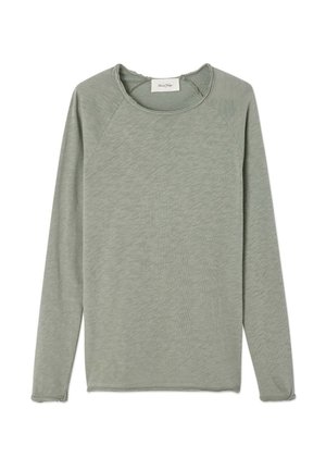 Garām piedurknēm t-krekls no mīksta, gaiši zaļa auduma ar noapaļotu kakla izgriezumu un neapstrādātām malām. Raksturo raglāna piedurknes un brīvs piegriezums.