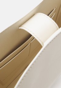 Beige nahkalaukun sisäosa, jossa on sileä pinta, keskimmäinen jakaja ja useita korttipaikkoja järjestystä varten.