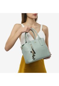 Borsa in pelle verde menta con doppi manici, forma strutturata e un portachiavi decorativo. Finitura testurizzata con dettagli hardware in tonalità oro.