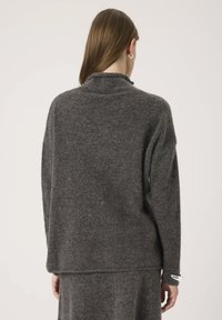 Maglione grigio in lana con colletto alto e vestibilità rilassata. Texture morbida, spalle scese e maniche lunghe con risvolti.