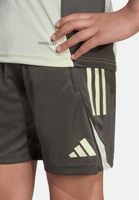 Sportshirt in lichtgroen met logo, gecombineerd met donkergrijze shorts met lichtgroene strepen en een gladde afwerking.