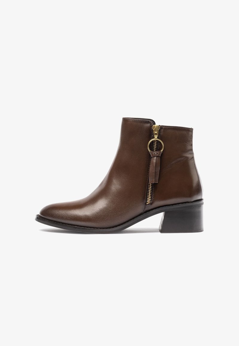 Bottine en cuir brun avec une finition lisse, fermeture éclair sur le côté et un talon carré. Elle présente un bout légèrement arrondi et un accessoire de tirette de fermeture éclair.