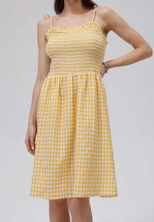 Geel geruit jurk met fashionably bodice met smock, gerimpelde halslijn en verstelbare bandjes. De stof is lichtgewicht met een zachte textuur.