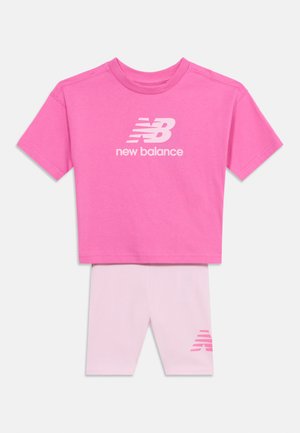 Crop top rosa a maniche corte di New Balance con pantaloncini da ciclista coordinati in rosa chiaro, con logo New Balance rosa sulla gamba sinistra.