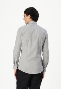 Camicia a maniche lunghe da uomo in tessuto intrecciato con un motivo geometrico bianco e blu, caratterizzata da un design aderente, colletto a punta e polsini con bottoni.