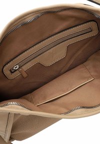 Beige leather handbag interior with a zippered pocket and a flat pocket. Smooth texture with contrasting brown lining and metallic zipper details.