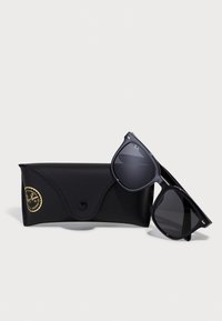 Ochelari de soare Ray-Ban negri cu lentile închise și accente metalice, așezați lângă un toc din piele neagră cu un logo auriu și închidere tip snap.