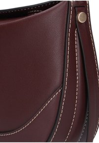 Bordeauxrode leren schoudertas met contrasterende witte stiksels, gebogen ontwerp en decoratieve gouden hardware accenten. Gladde textuur.