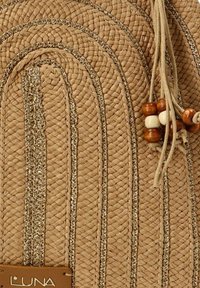 Bolso de paja tejido en tonos naturales con líneas curvas, acentos metálicos y cuentas de madera decorativas unidas a un cierre con cordón.