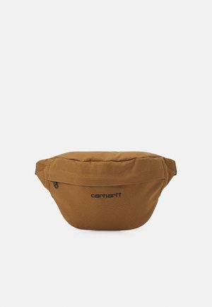 Brązowa saszetka Carhartt z przednią kieszenią na zamek i czarnym haftowanym logo na środku przodu.