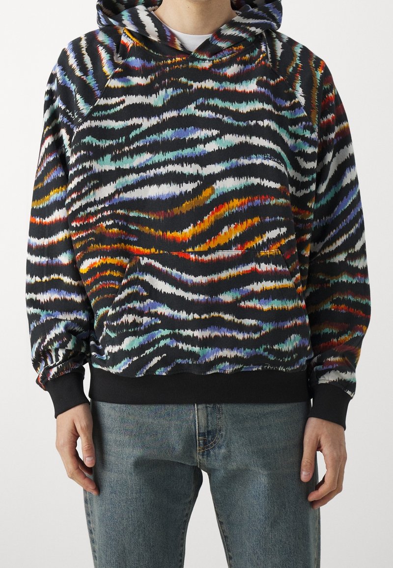 Sudadera con capucha en vibrantes patrones de olas multicolores sobre un fondo negro, hecha de una tela suave con puños y dobladillo acanalados.