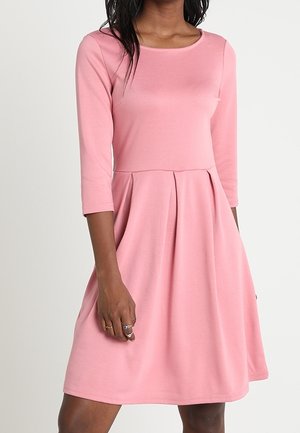 Różowa sukienka z okrągłym dekoltem, rękawami do połowy przedramienia i rozkloszowanym dołem. Wykonana z miękkiego materiału, z plisami w talii.