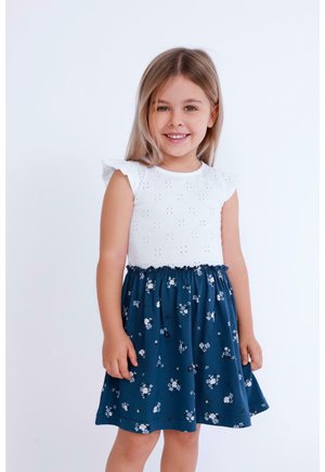 Katoenen jurk met een witte eyelet top en een marineblauwe bloemenrok. Kenmerkt zich door korte gerimpelde mouwen en een elastische tailleband voor comfort.