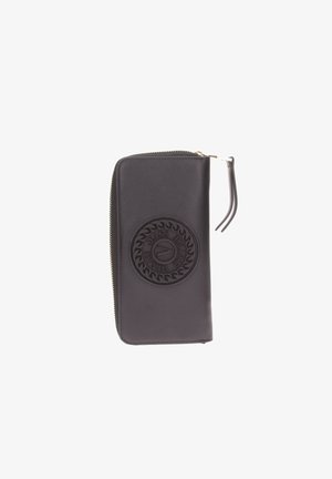 Portafoglio in pelle nera con un emblema circolare testurizzato e scritte, chiusura con zip e un cinturino da polso. Superficie liscia e forma rettangolare.