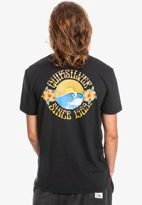 Černé bavlněné tričko s barevným grafickým designem na zadní straně, který zobrazuje slunce, vlnu, květiny a text "Quiksilver Since 1969".