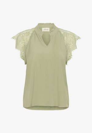 Vaaleanvihreä pusero, jossa on avainreikäkaulus ja pitsihihat. sisältää teksturoitua pitsiä ja rentoa leikkausta. Pehmeä kangas, jossa on sujuva pinta.