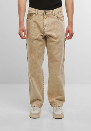 Beige cargo pants with a relaxed fit, featuring front and side pockets, faded texture, and reinforced stitching.
