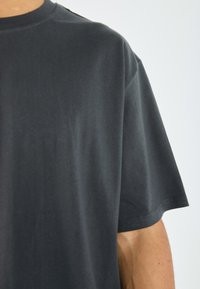 Dark gray cotton t-shirt with a round neck, short sleeves, and smooth texture. Minimalistic design, no visible patterns or accents.