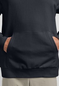 Schwarzer, strukturierter Kapuzenpullover mit Kängurutasche, gerippten Bündchen und Saum sowie einer lockeren Passform. Der Stoff wirkt robust und angenehm zu tragen.