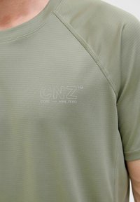 Olivovo zelené športové tričko s odvodom vlhkosti a textúrovanou tkaninou. Má okrúhly výstrih a vyšitý logo "CNZ CORE NINE ZERO".