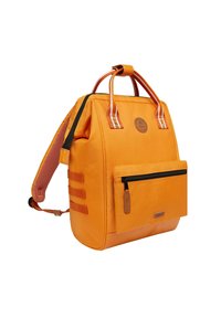 Oranje canvas rugzak met dubbele handgrepen, een verstelbare schouderband, een voorzak met rits en stoffen accenten. Bevat een rond logo.
